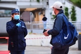 A police officer in a face mask and gloves pointing at a man