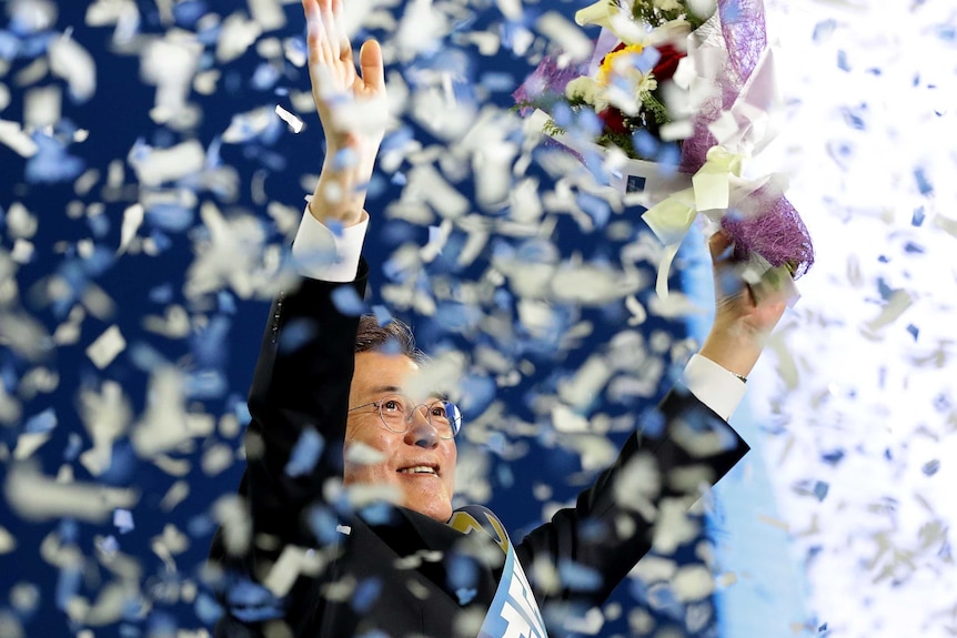 South Korean presidential election candidate Moon Jae-In stands in a shower of confetti.