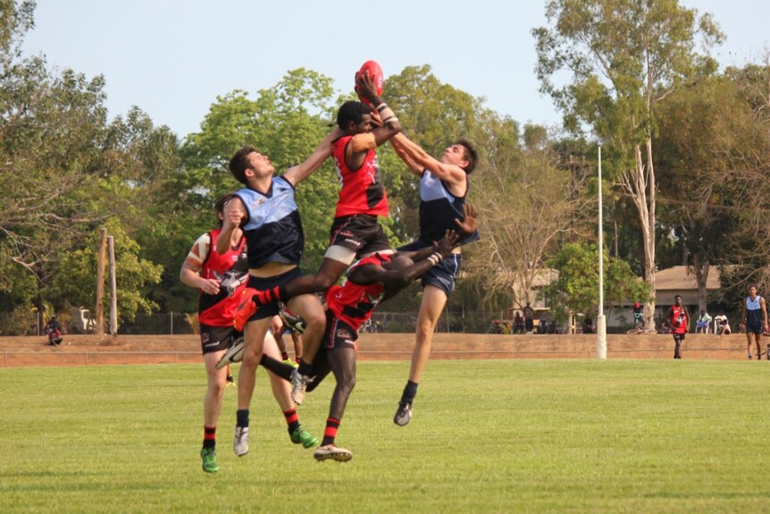Three Tiwi Bombers players leap for the ball