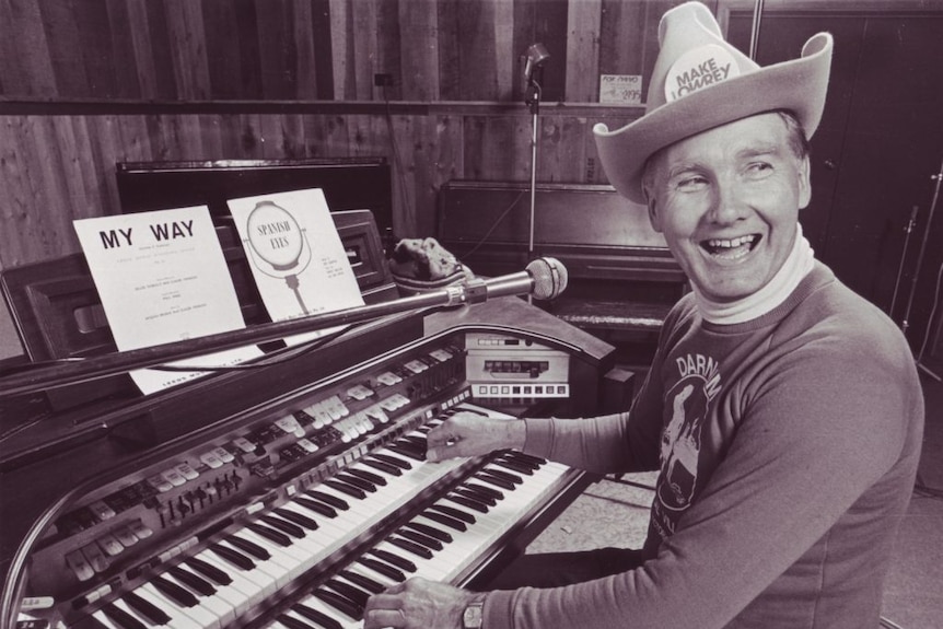 Animated man dressed in cowboy hat performs on an organ.