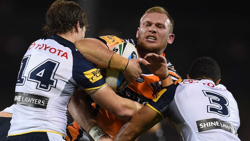 Matthew Lodge of the Tigers is tackled by the Cowboys' Rory Kostjasyn (L) and Justin O'Neil in 2015.