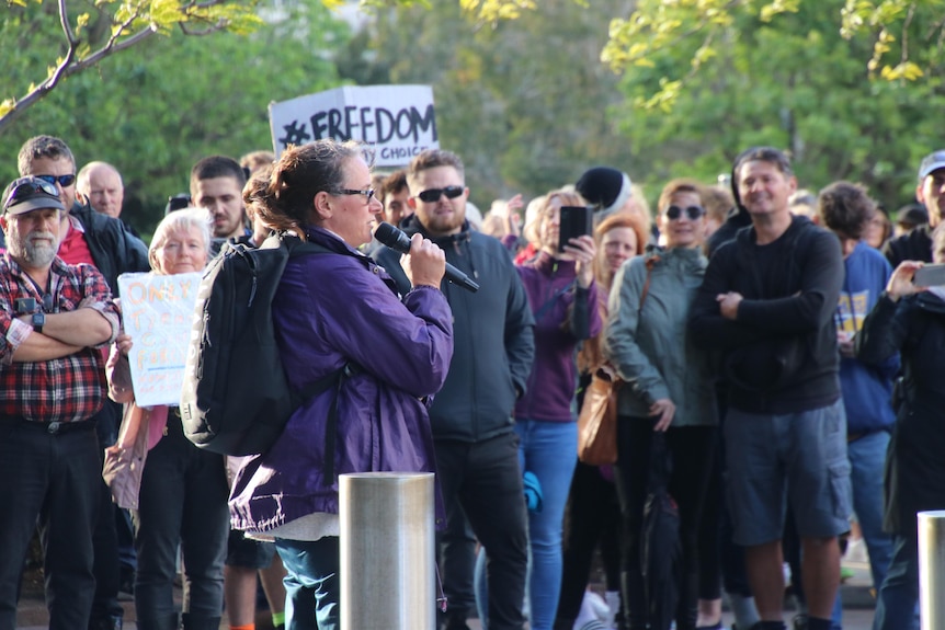 A woman addresses the crowd at an anti-vaccination rally.