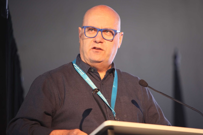 Craig Ritchie stands at a lectern while speaking at the National Native Title Conference in Broome.