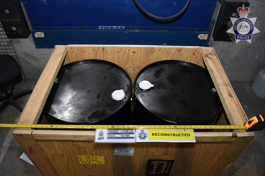 Two steel drums sit inside a crate.