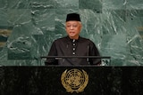 Malaysia's PM standing in front of microphone for a speech. 