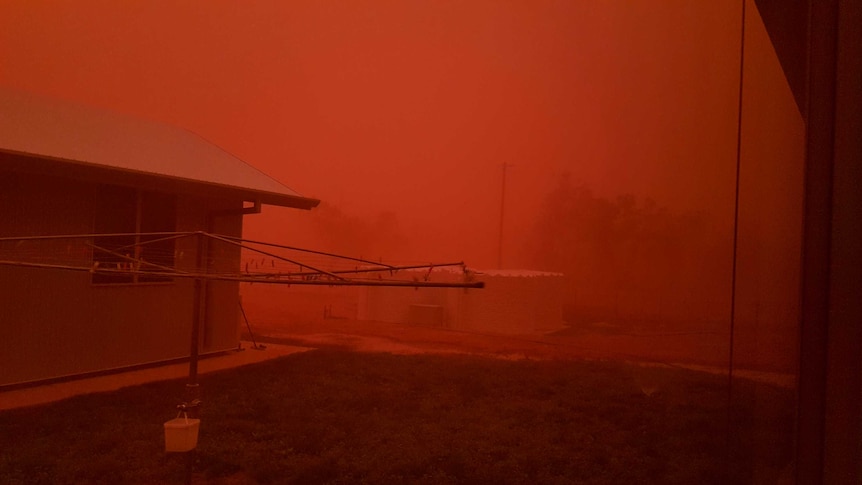 A backyard coated in a thick shade of red dust during a dust storm.