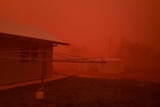 A backyard coated in a thick shade of red dust during a dust storm.