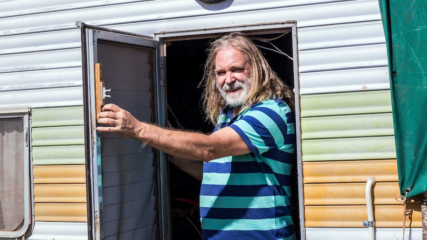 Roland Gopel stands in the doorway of his caravan.