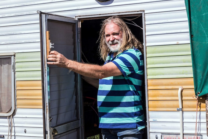 Roland Gopel stands in the doorway of his caravan.