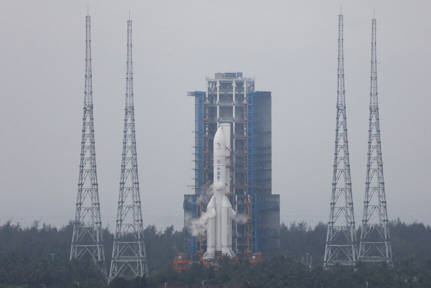 A rocket sits atop a launch pad surrounded by four towers