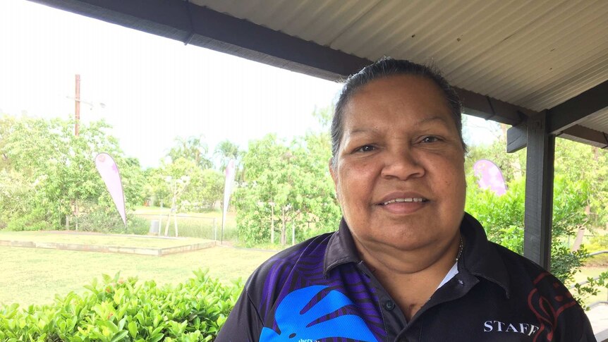 A woman in a bright shirt smiles at the camera