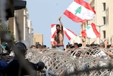 Lebanese protesters wave the national flag in front of a barbed wire fence during a demonstration