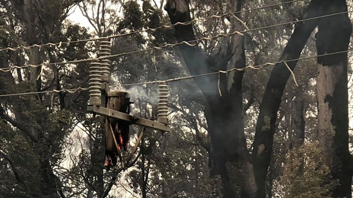 A utility pole destroyed by bushfires continues to burn.