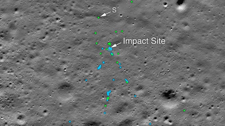 A grey image of a lunar surface with craters and blue and green spots marking spacecraft debris and disturbed soil.