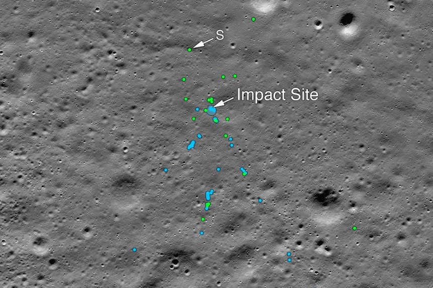 A grey image of a lunar surface with craters and blue and green spots marking spacecraft debris and disturbed soil.