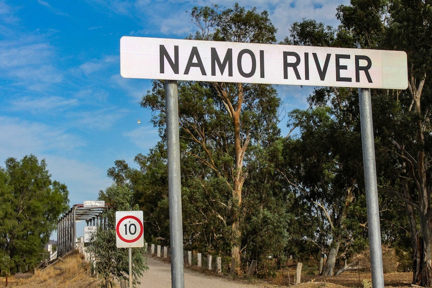 A sign saying "Namoi River" in front of trees and a bridge.
