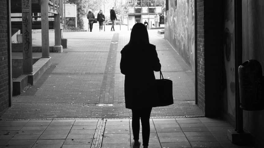 Woman in shadow walking down a tunnel.