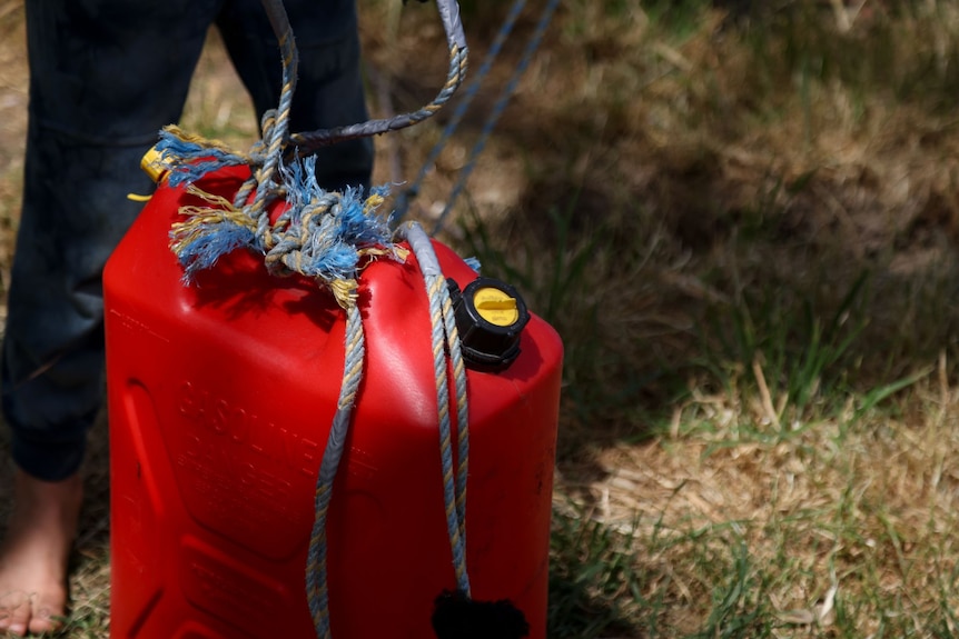 A jerry can with ropes attached to the top handle
