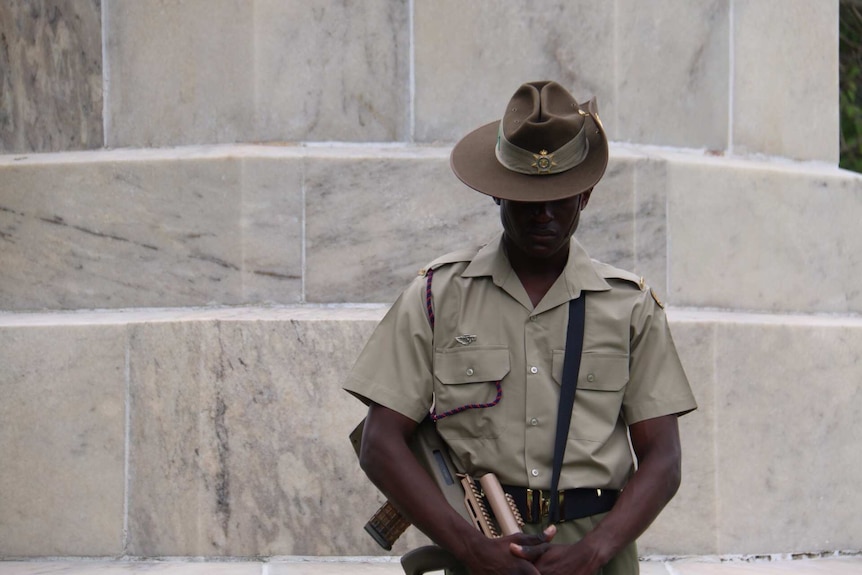 A soldier in a slouch hat bows his head.