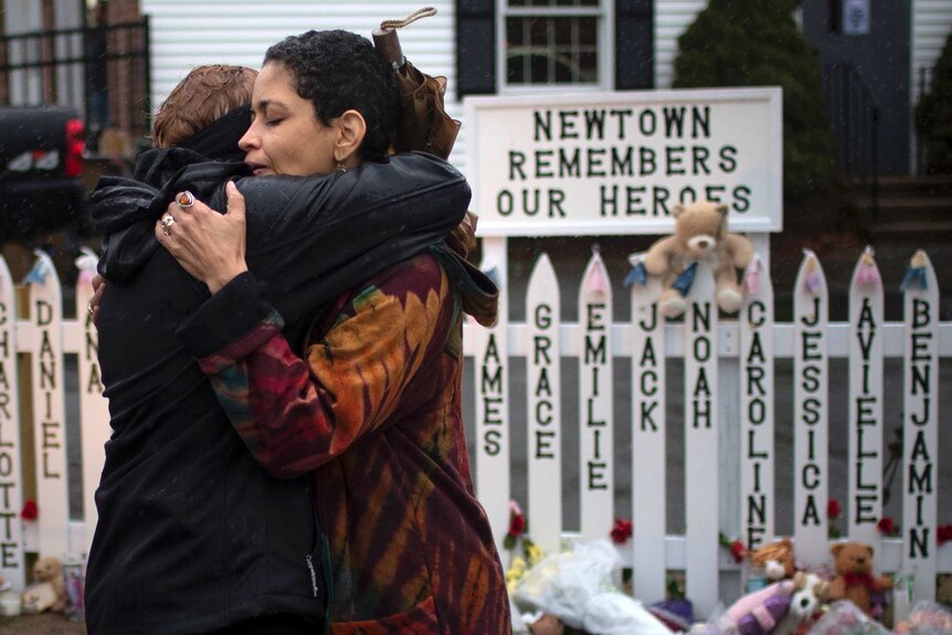 Women embrace after observing a moment of silence nearby Sandy Hook Elementary in Newtown.