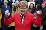 Scottish First Minister Nicola Sturgeon in a red blazer cheering.