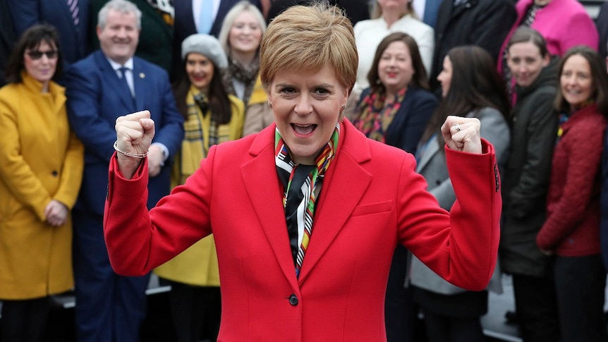 Scottish First Minister Nicola Sturgeon in a red blazer cheering.