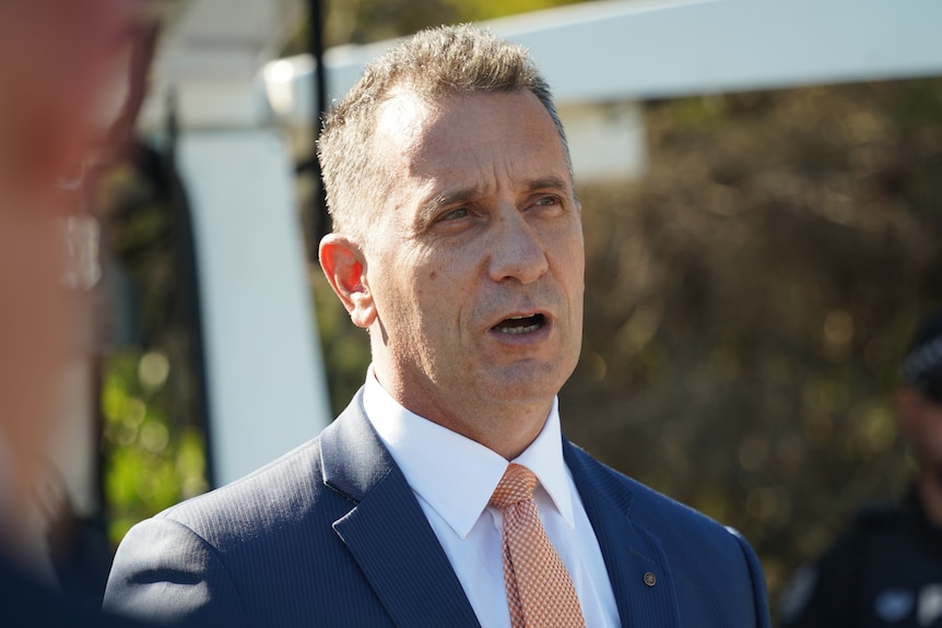 A man in a suit and tie speaks at a press conference