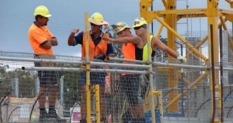 A group of construction workers stand on a building site.