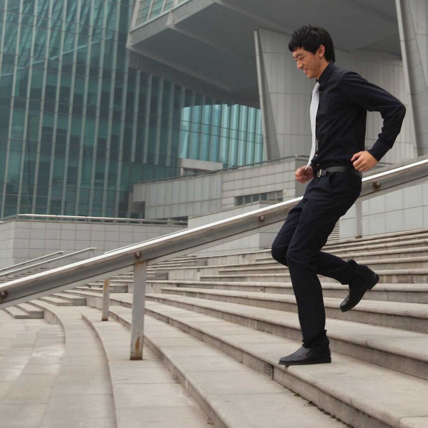 Man in suit running down stairs outside