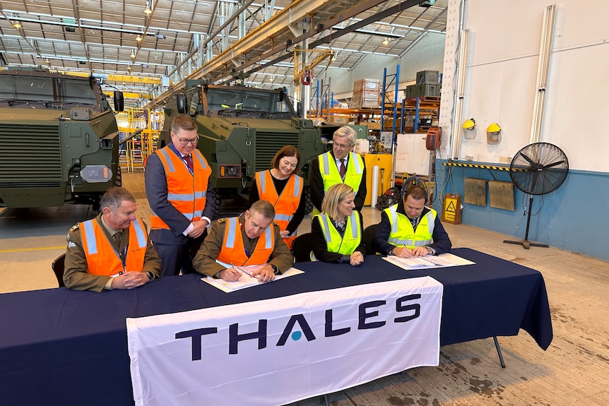 people in high vis signing a contract at a table
