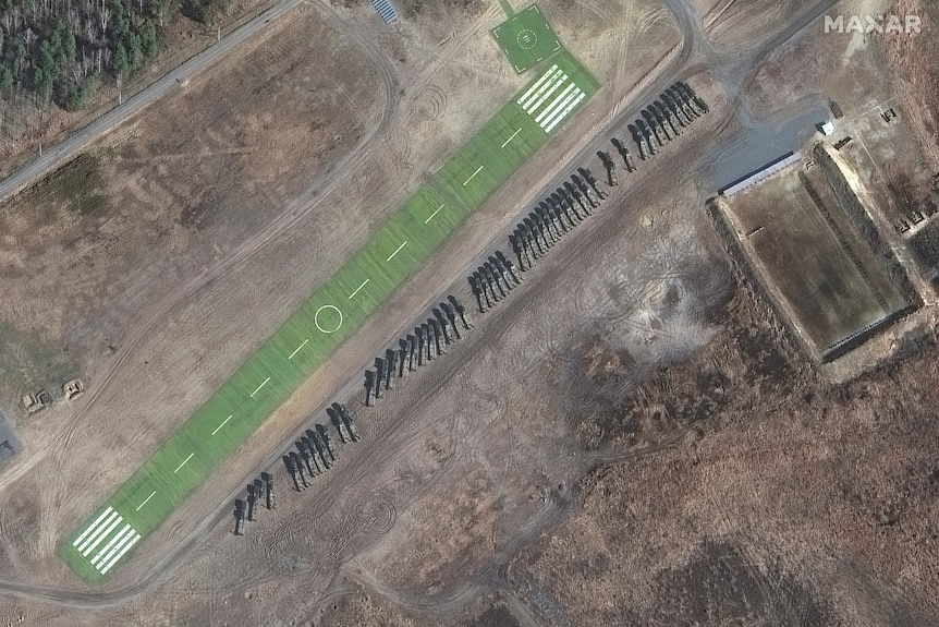 A satellite image shows a long line of military trucks parked