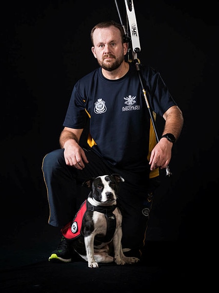 An Invictus Games competitor kneels with his therapy dog