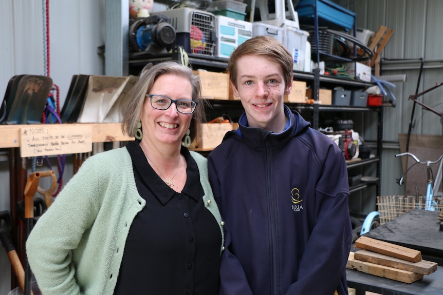 Kate and Harper stand together smiling inside a workshop in a shed.