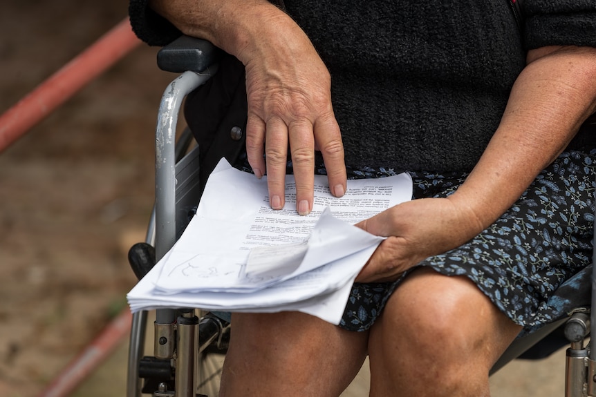 A woman in a wheelchair looks at a document