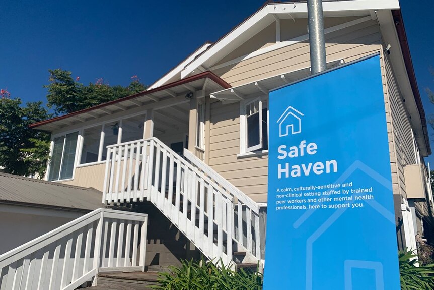 The front of house with stairs and a large blue sign that says Safe Haven.