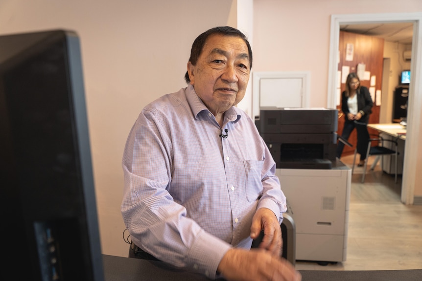 Harry Hunt wearing a button-up shirt and sitting at a computer in an office.