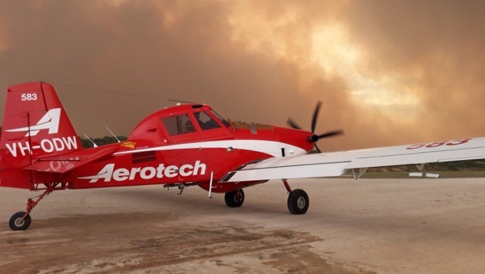 plane stationary on ground with smoke in the background