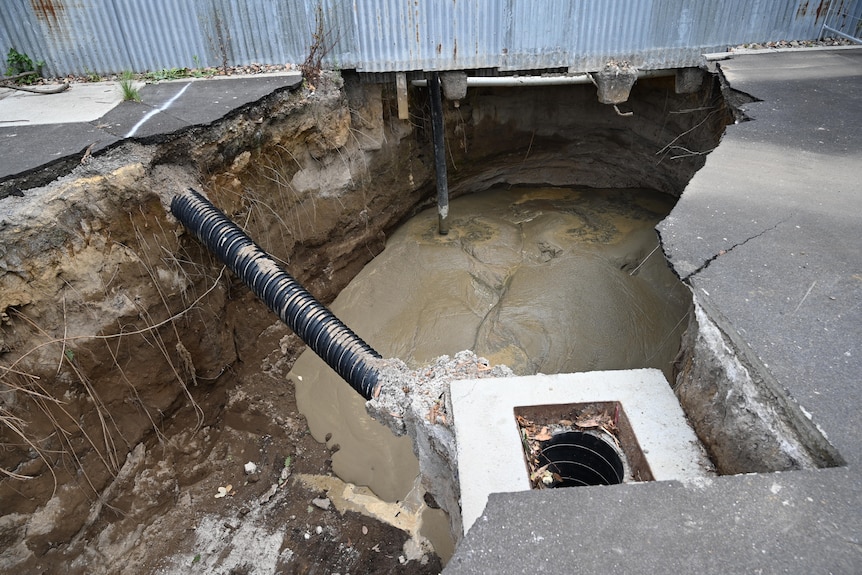 A cement and sand mixture is pumped into the bottom of a sinkhole.
