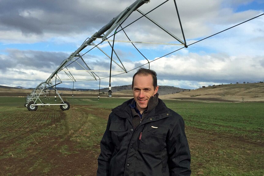 Tasmanian farmer Richard Hallett stands in front of irrigation equipment.