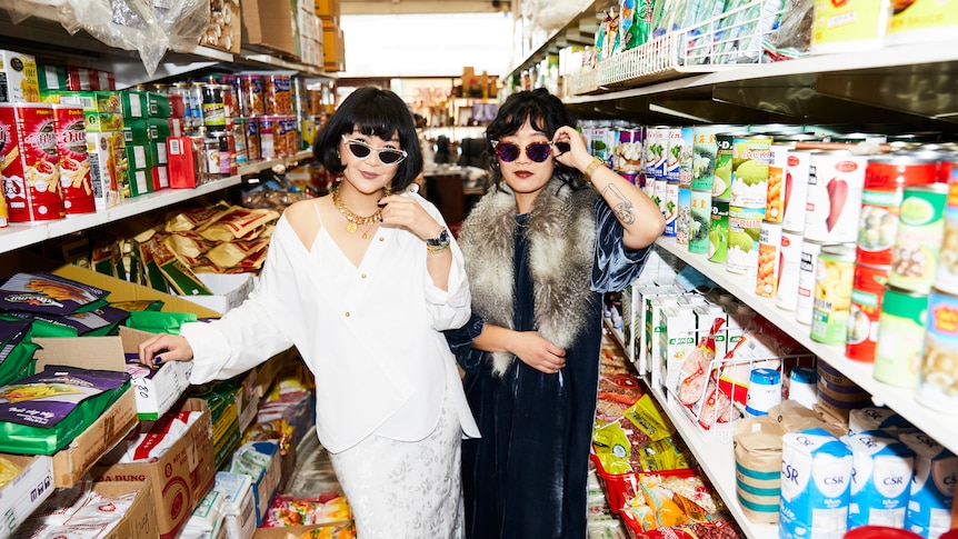 Co-authors Rosheen Kaul and Joanna Hu pose wearing stylish sunglasses in the isle of a grocery store. 