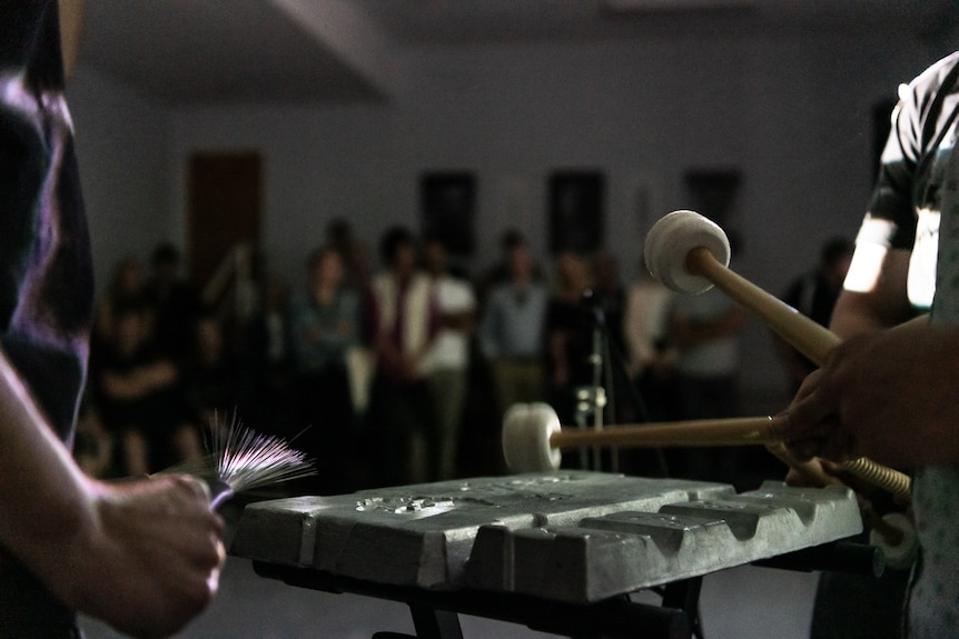 A man hits a zinc ingot with a drum mallet