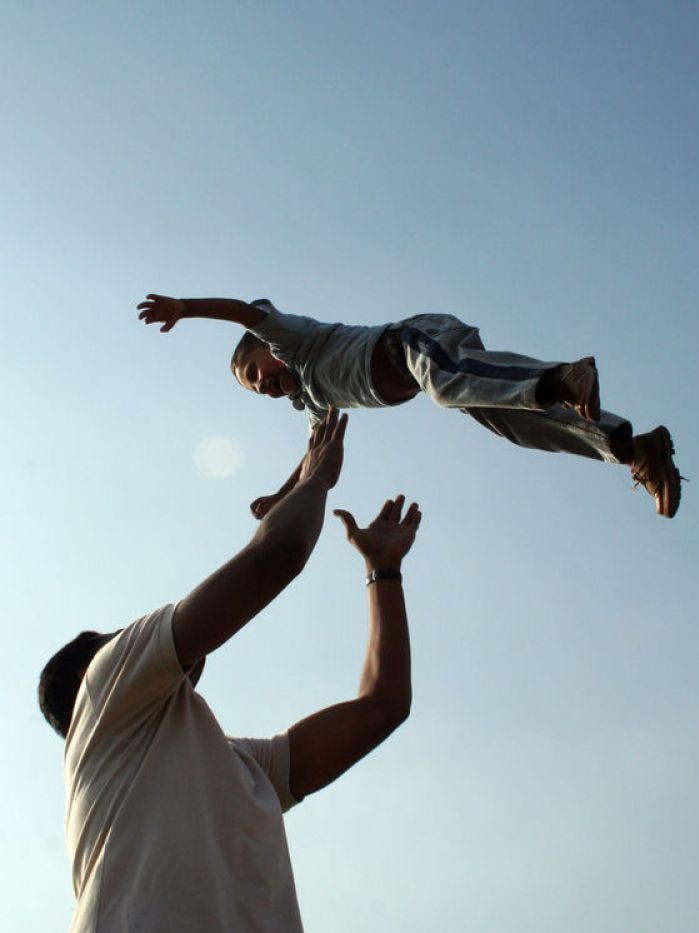 A father throws his young son up into the air.