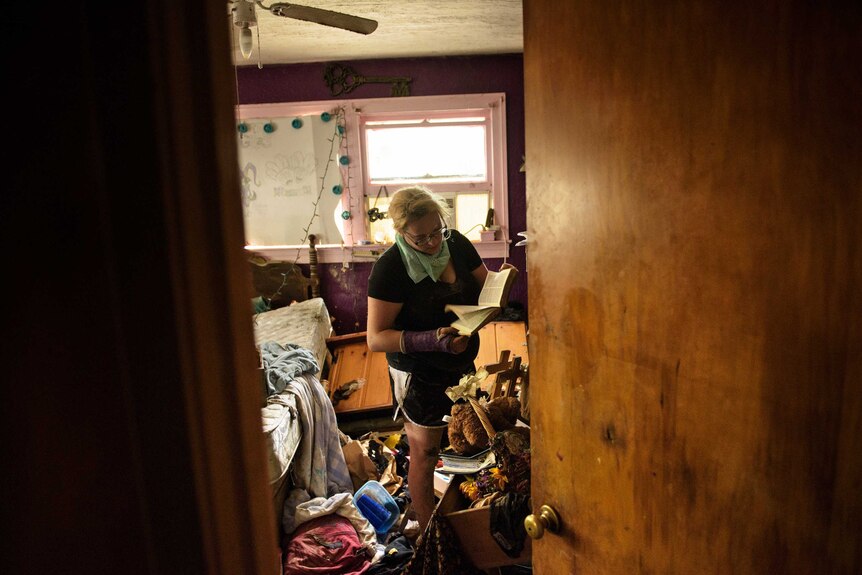 Looking through a doorway at Louisiana resident Cheyenne Hughes trying to salvage items from her flooded home.