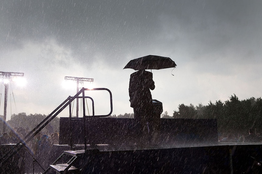 President Barack Obama stands on a stage in the rain