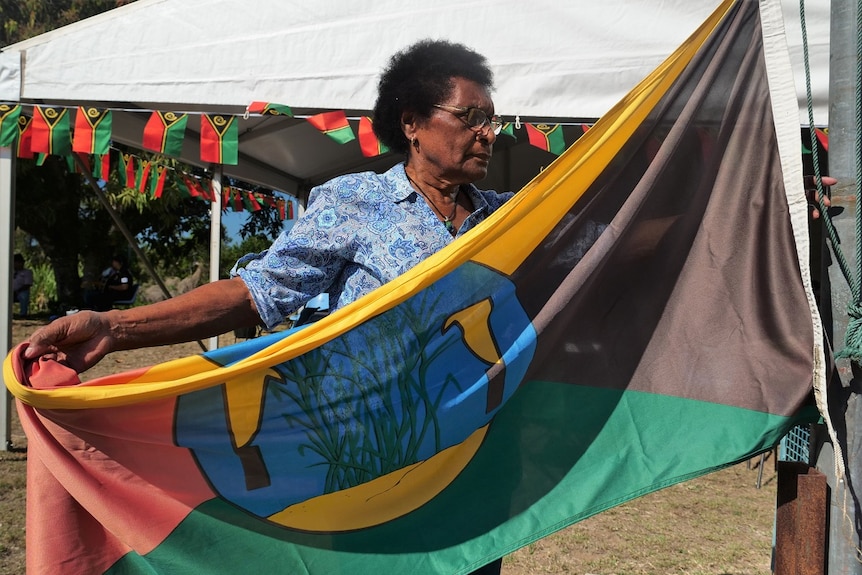 Doris Leo attaches the Australian South Sea Islander United Council flag to a pole.