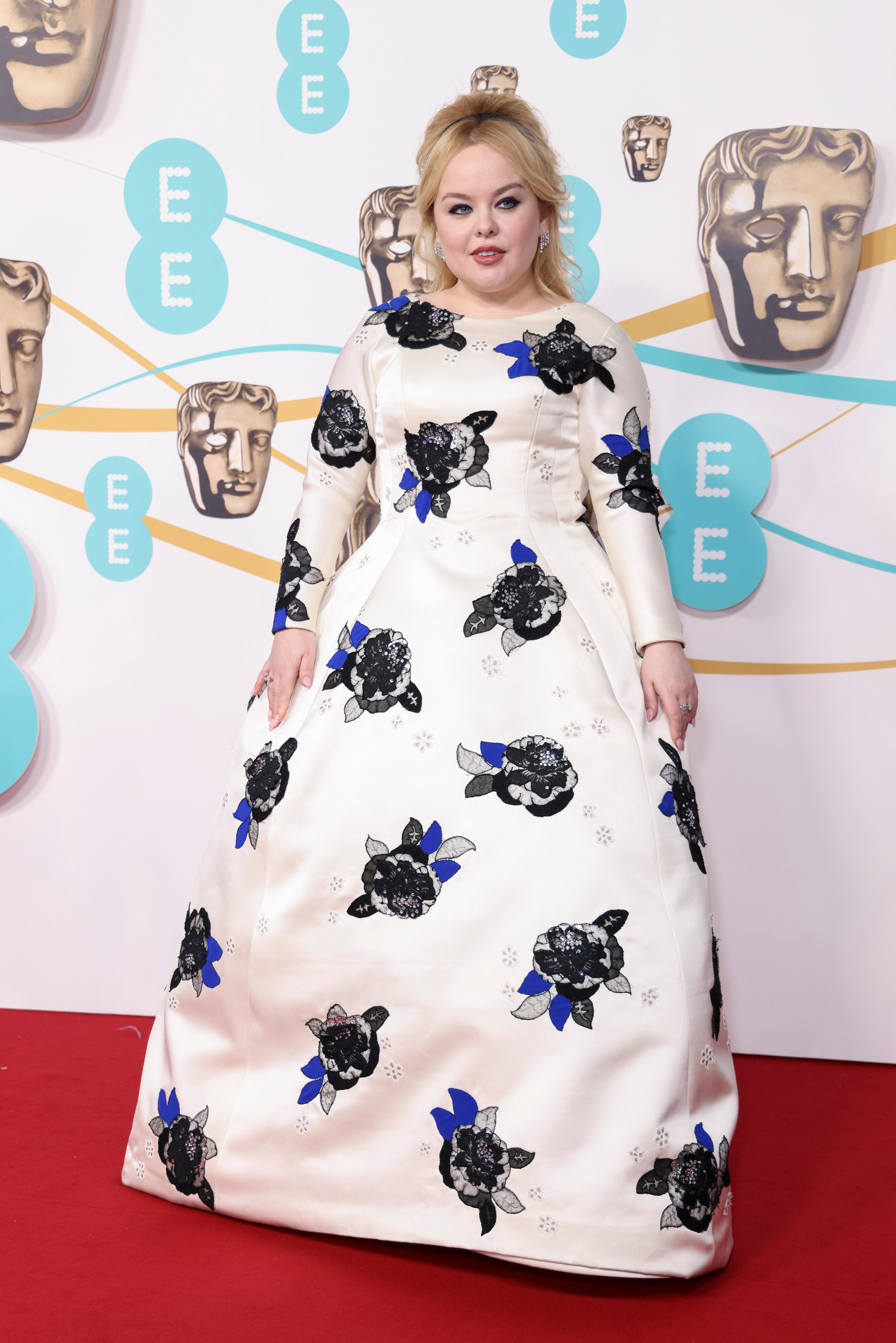 A woman wearing a white gown with flower prints on the red carpet 