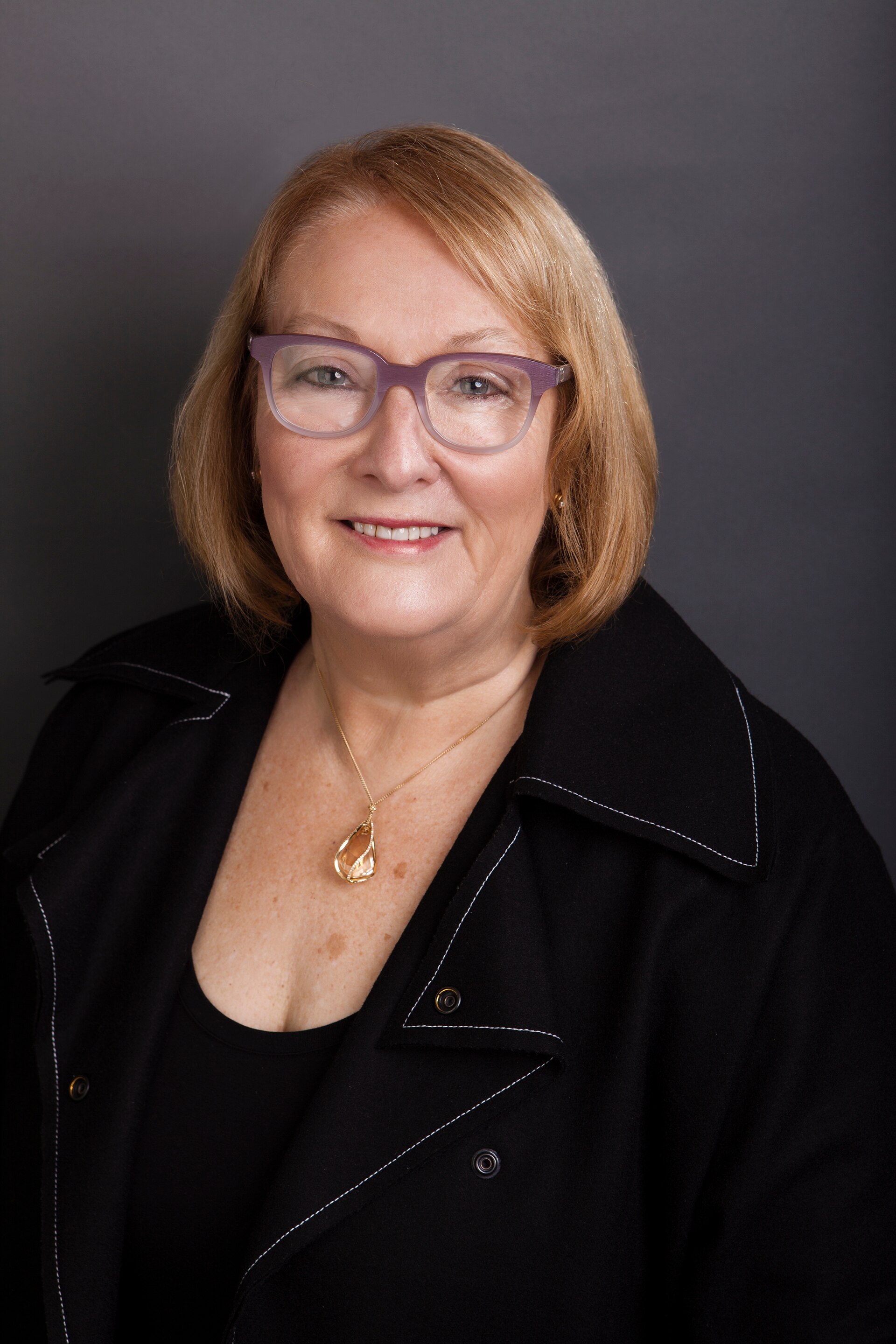 Woman wearing glasses smiles for picture