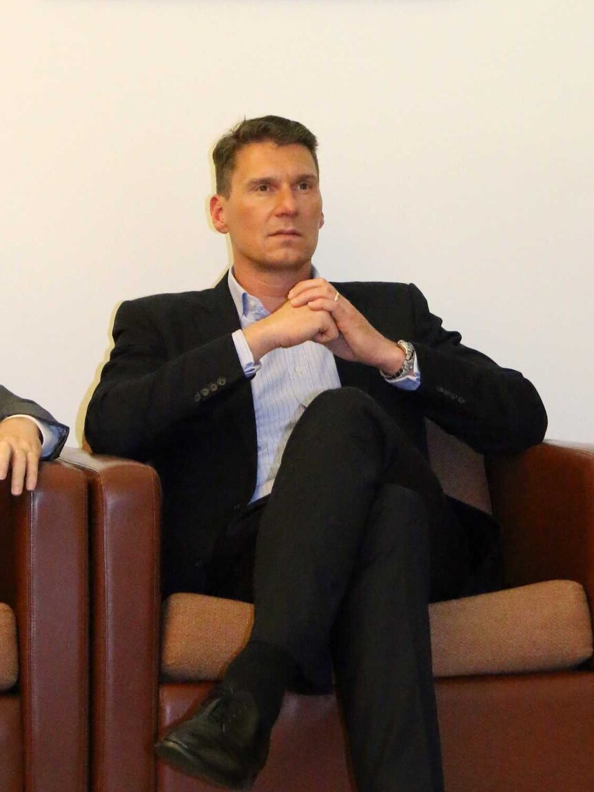 Cory Bernardi sits underneath a portrait of PM Malcolm Turnbull during a Coalition party room meeting in Canberra.