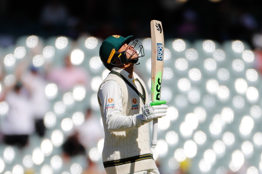 Usman Khawaja looks up and points his bat to the sky