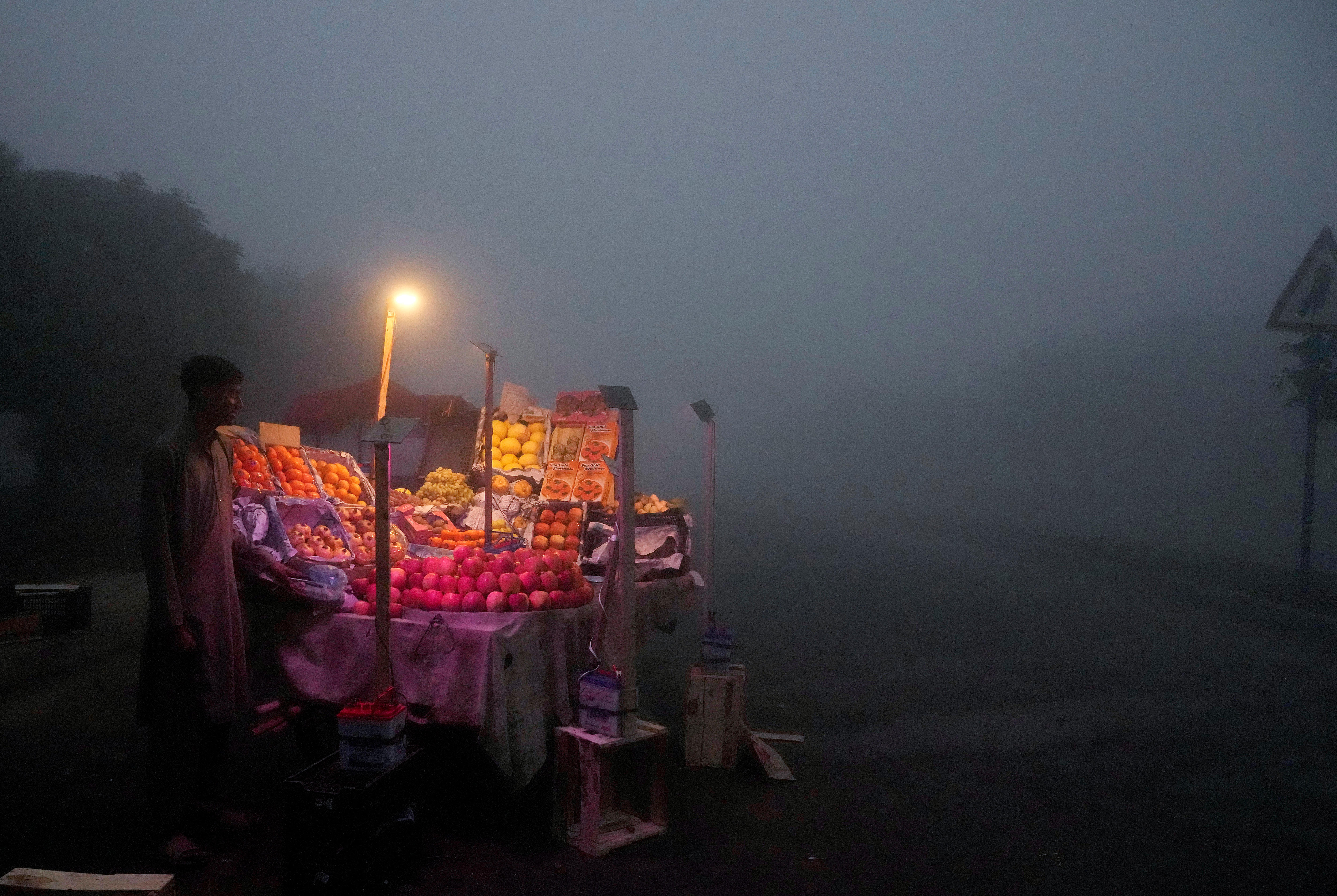 A fruit seller arranges his stall in early morning as smog envelopes the area of Lahore, Pakistan.